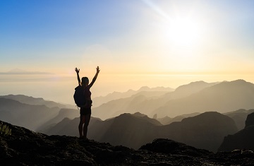 Picture: Woman successful hiking climbing silhouette in mountains, motivation and inspiration in beautiful sunset and ocean. Female hiker with arms up outstretched on mountain top looking at beautiful night sunset inspirational landscape.