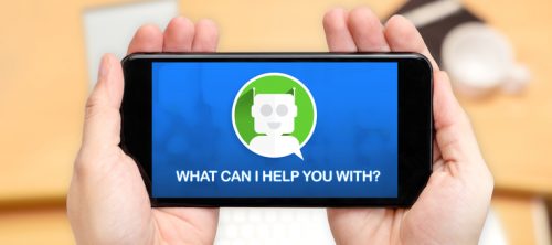 Picture: Watching two hand holding mobile phone with Chat bot and what can i help you with? with blur desk office background